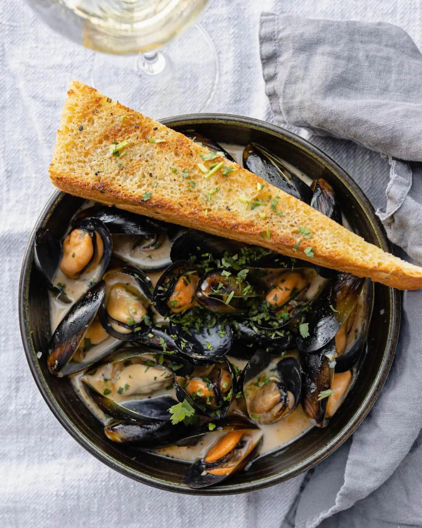 Mussels and bread &mdash; steamed mussels in a creamy white wine broth with grilled garlic bread at notable - The Steakhouse in northwest Calgary