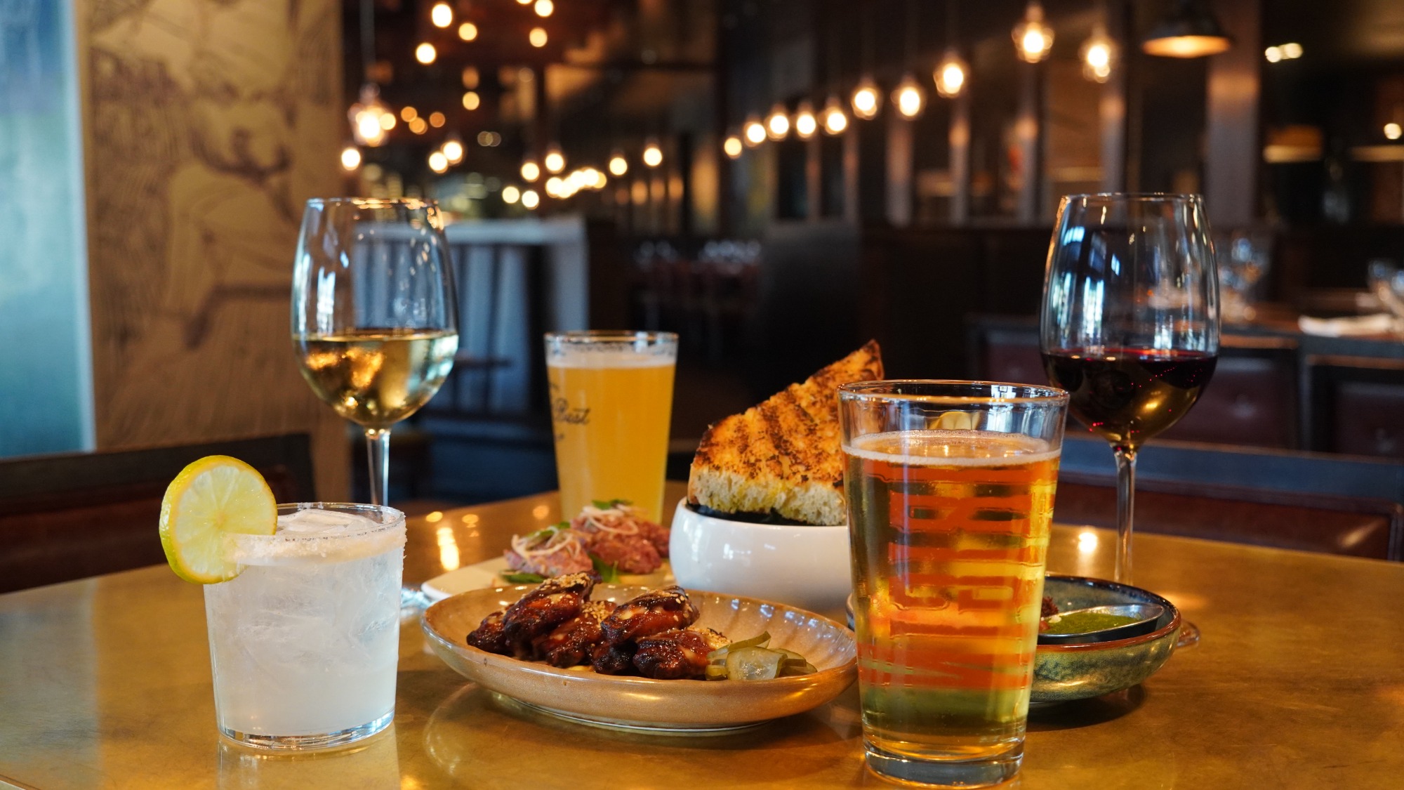 Ember Hour spread at NOTABLE - The Steakhouse: gochujang wings, toast bites, garlic cheese grilled bread, a margarita, beer and wine on the lounge bar