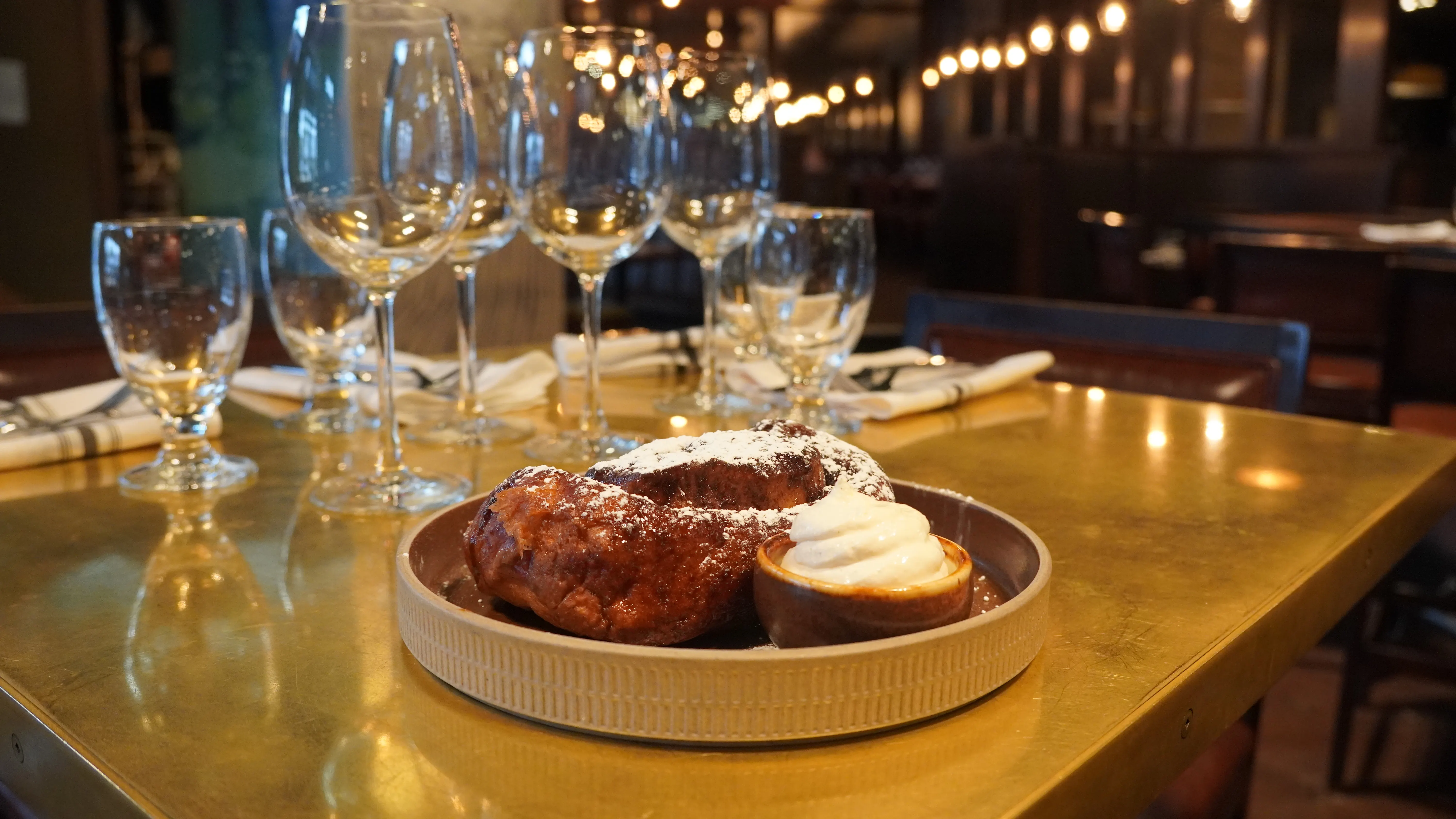 House-baked bread with whipped butter on a brass table set with wine glasses in the dining room at notable - The Steakhouse, Calgary