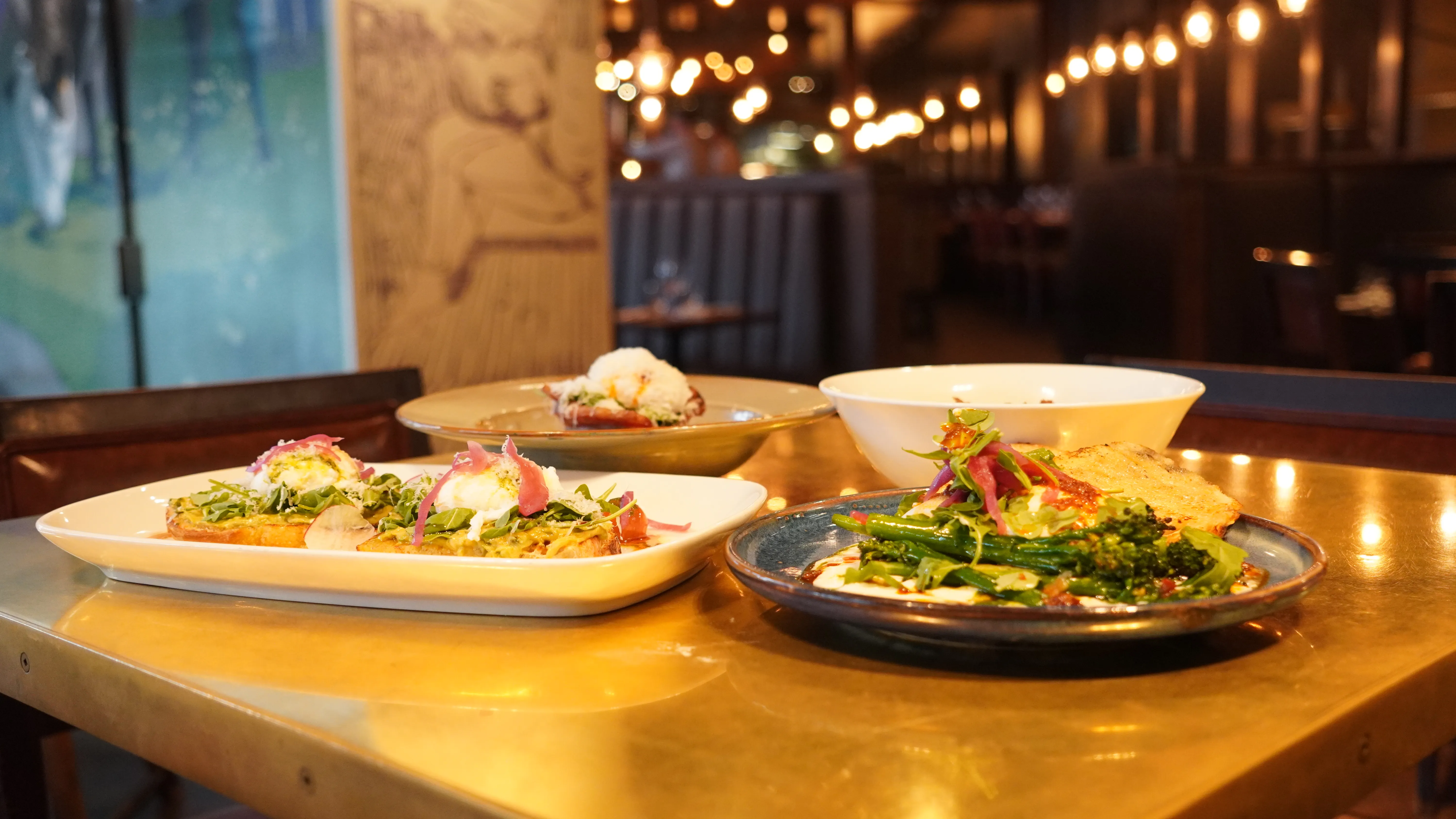 Shared plates spread across a table in the dining room at notable - The Steakhouse on Bowness Road NW, Calgary